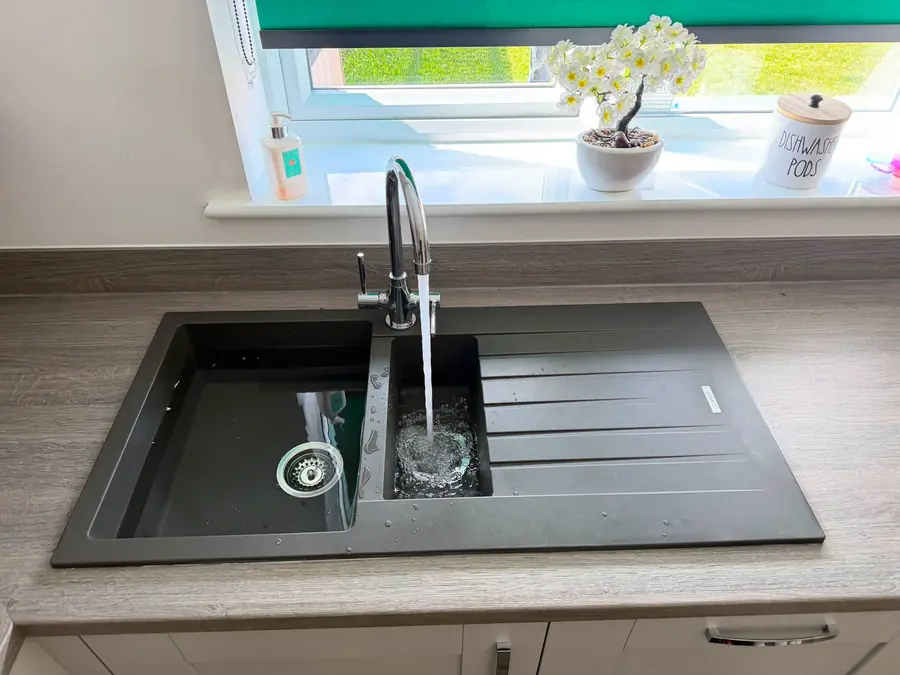 Black composite kitchen sink and mixer tap installation